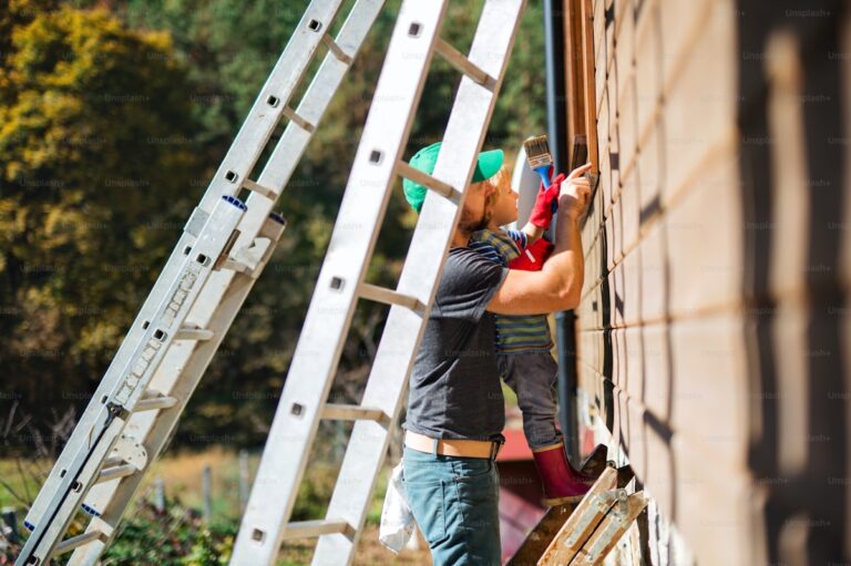 Father and child painting house exterior in summer