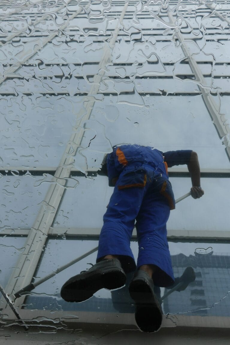 Professional window cleaner working on glass exterior - window cleaning prices in DFW