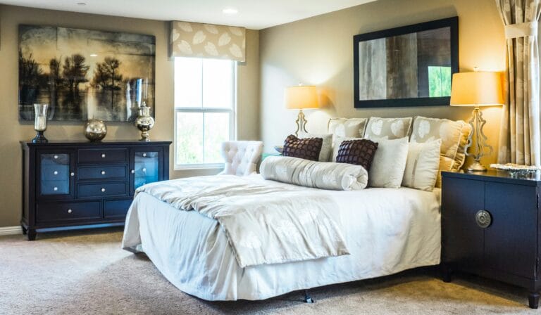 Neatly made bed with clean linens in a tidy, styled bedroom
