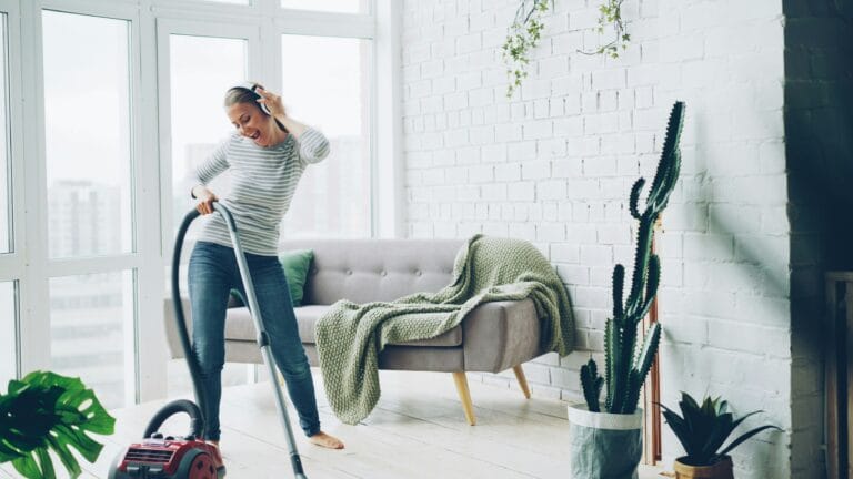 Woman vacuuming the carpet in a bright, tidy modern living room