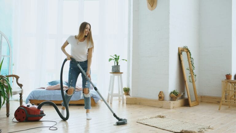 Person cleaning the floor of an empty, bright, freshly vacated room